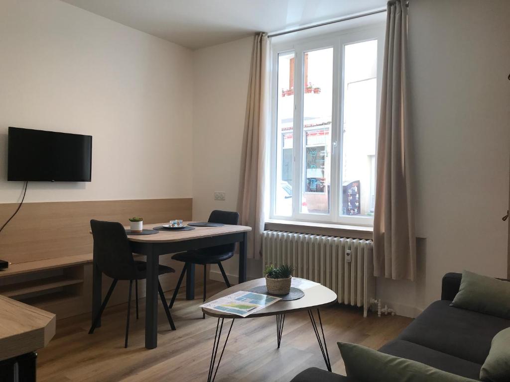 - un salon avec une table, un canapé et une fenêtre dans l'établissement LE LARBAUD - Hypercentre - Clim - Thermes- RDC, à Vichy