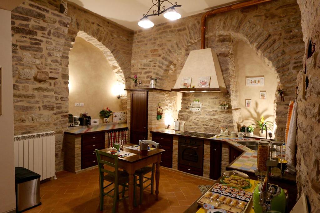 a kitchen with stone walls and a table with chairs at La Casina Colorata in Assisi
