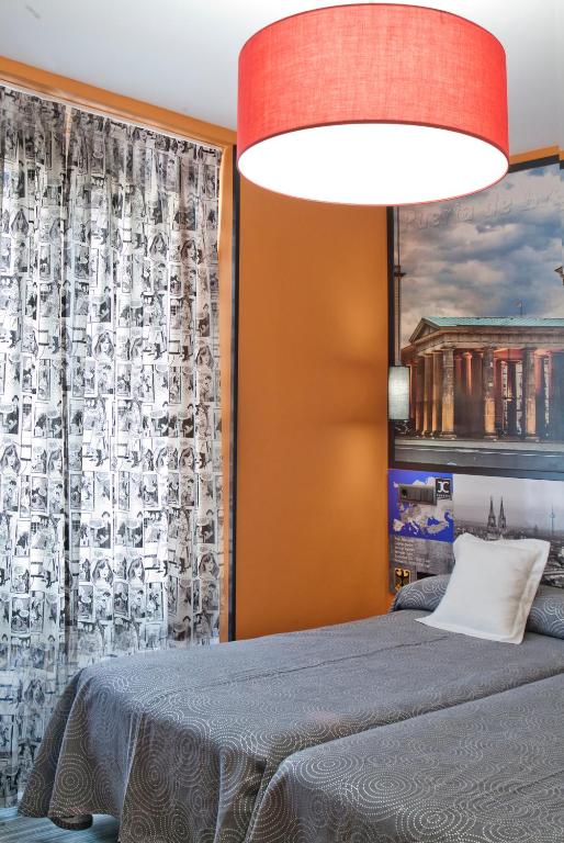a bedroom with a bed and a red lamp at JC Rooms Santo Domingo in Madrid