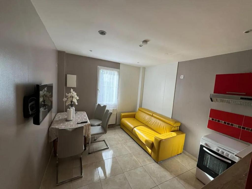 un salon avec un canapé jaune et une table dans l'établissement Appartement moderne à Villiers-le-Bel - 35 m² - Pour 4 personnes., à Villiers-le-Bel