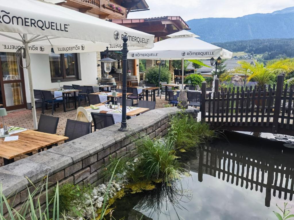 a restaurant with tables and chairs next to a body of water at Hotel Kärntnerhof & Suiten 3-Stern Superior in Lake Pressegg