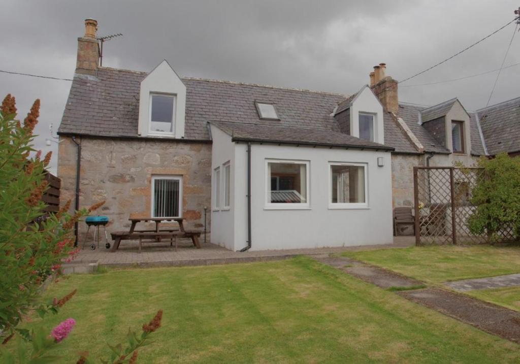 a house with a picnic table in a yard at Mike's 3-bedroom Countryside Cottage in Alness
