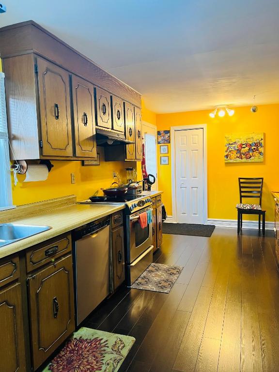 a kitchen with yellow walls and stainless steel appliances at Cozy House B&B in Niagara Falls