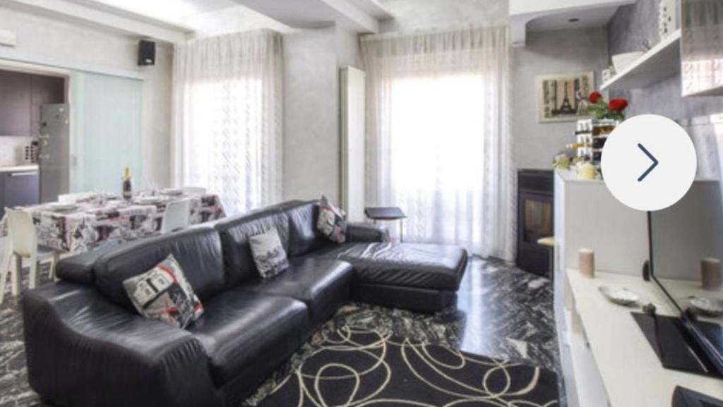 a living room with a black leather couch and a table at Mediterraneo 6 in Reggio Calabria