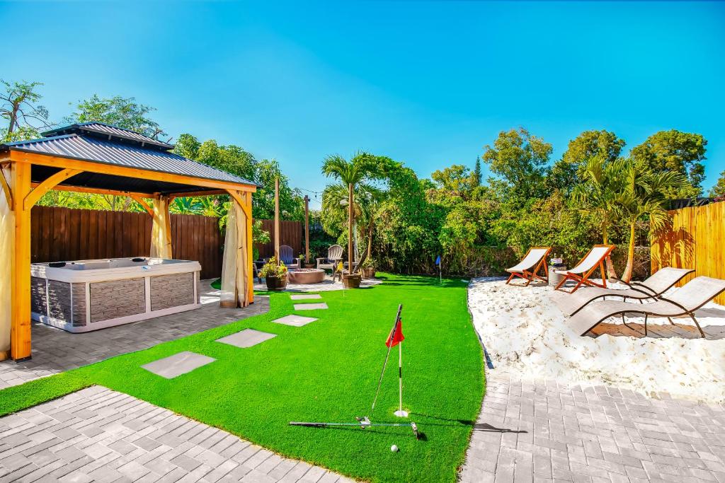 a backyard with a lawn with chairs and a gazebo at Coastal Farmhouse with mini Golf, Private Beach &Spa in Naples