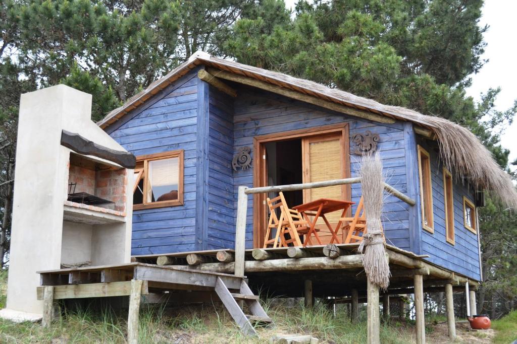 a blue house with a thatched roof at Arándanos in Punta Del Diablo