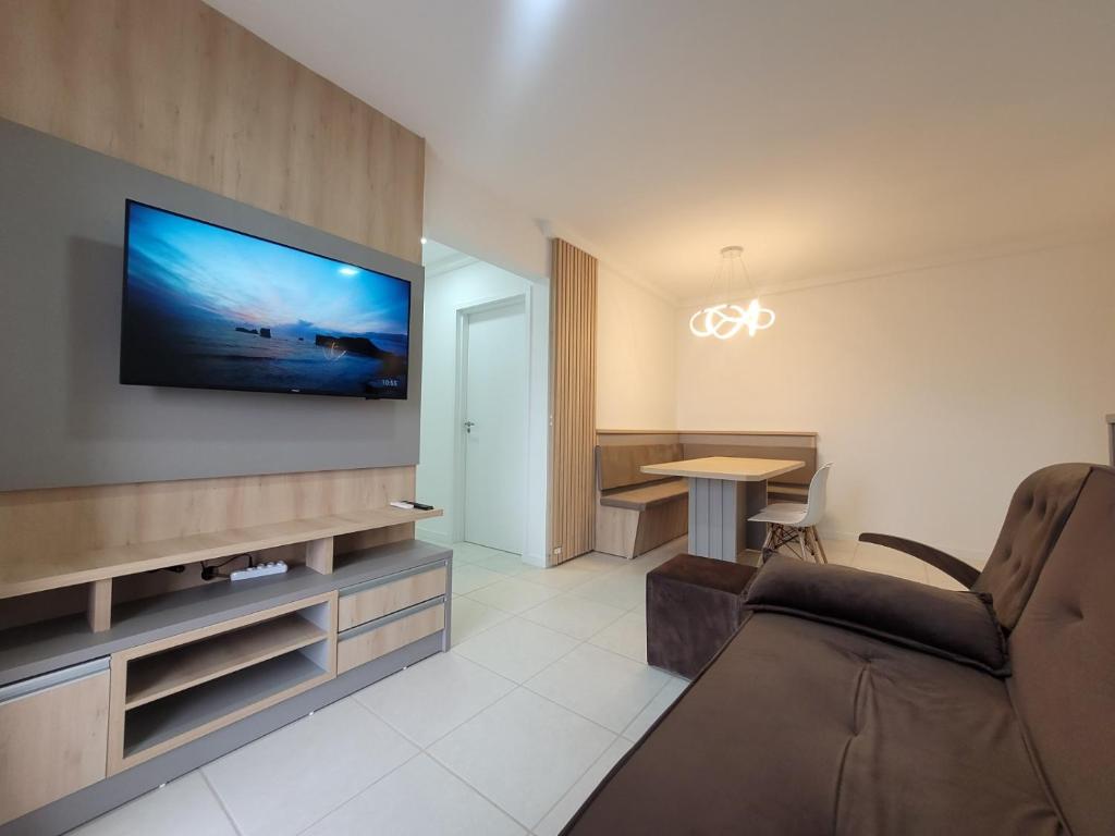 uma sala de estar com uma televisão na parede em Apartamento novo, vista mar, 150m da praia em Piçarras