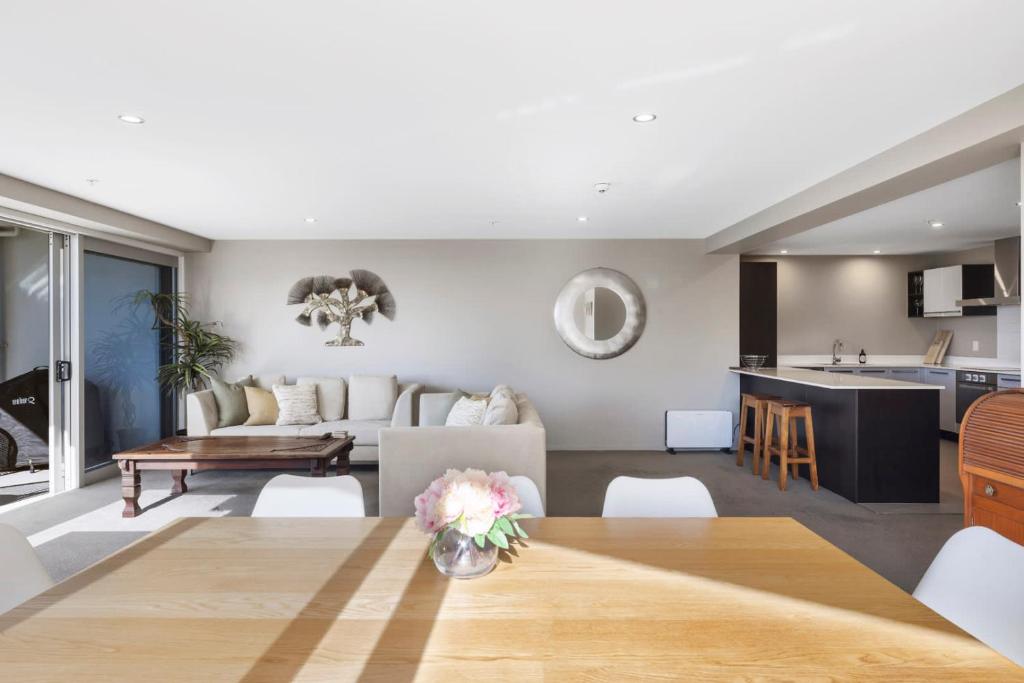 a living room with a table and a kitchen at Sun filled & Spacious with Ocean Views & beach in Mount Maunganui