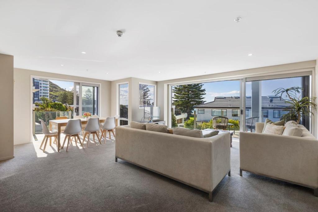 a living room with couches and a table and chairs at Sun filled & Spacious with Ocean Views & beach in Mount Maunganui