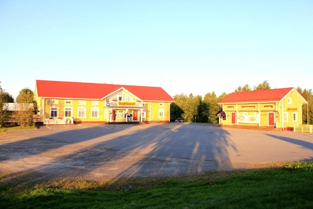 a yellow building with a red roof on a street at Koskikievari in Lappajärvi