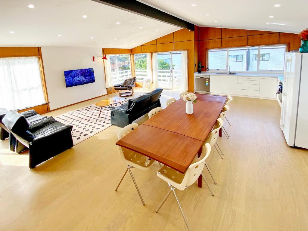 a kitchen and living room with a wooden table and chairs at Waterfront villa near IKEA and Sylvia Park in Auckland