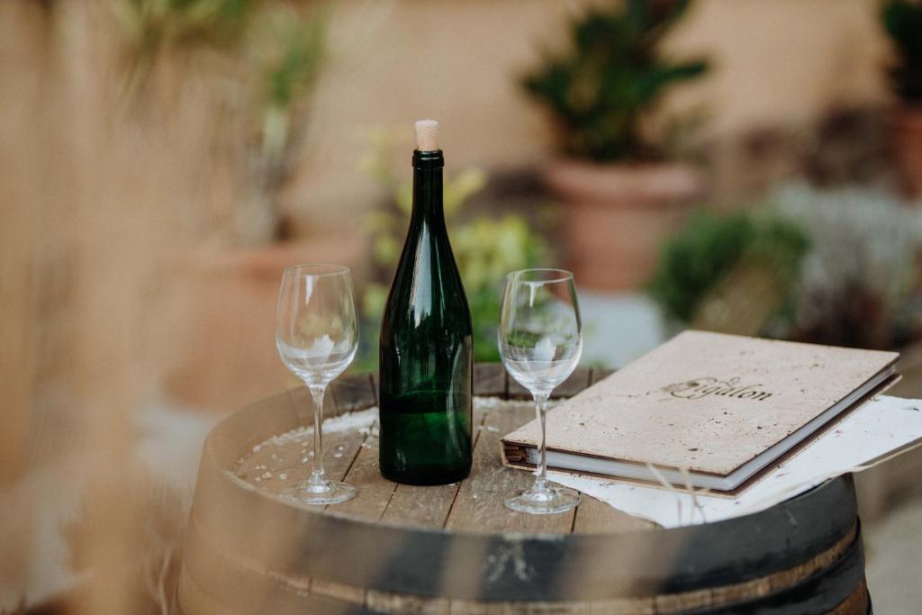a bottle of wine sitting on a barrel with two wine glasses at Hotel Restaurant Le Cigalon in Waldbillig