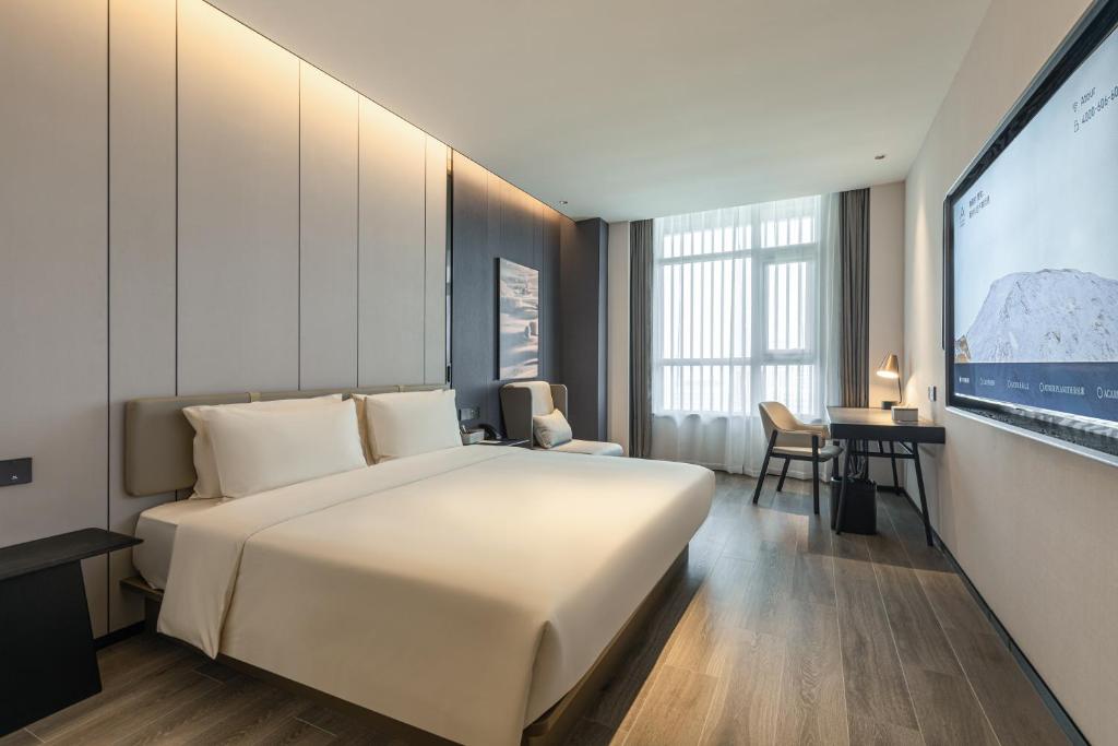 una camera con un grande letto bianco e una TV di Atour Hotel Yantai Penglai Government Centre a Penglai