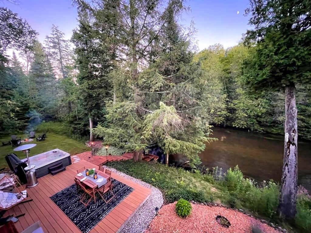 an aerial view of a deck with a table next to a river at Firefly Lodge! Boardman River! Hot Tub! Woodstove! in Traverse City