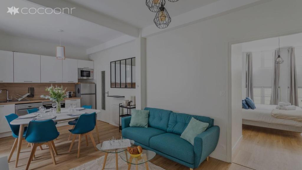 un salon avec un canapé bleu et une cuisine dans l'établissement Les Lauriers - dans l'Intramuros, à Saint-Malo