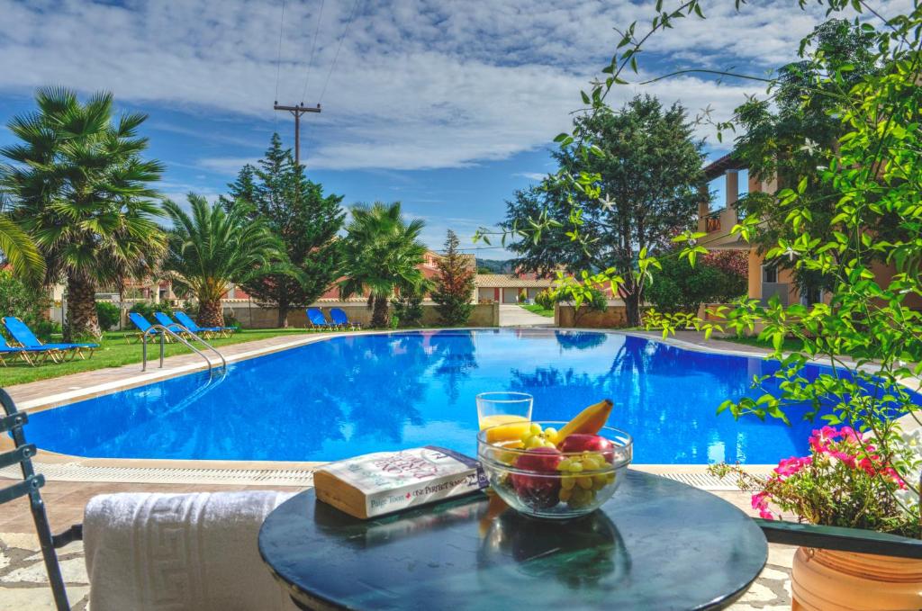 a bowl of fruit on a table next to a swimming pool at Jasmine Apartments in Sidari
