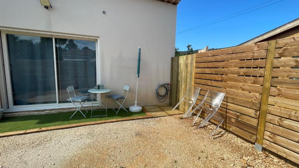 une terrasse avec deux chaises et une table en face d'une clôture dans l'établissement Studio calme avec jardin et parking privé, à La Ciotat