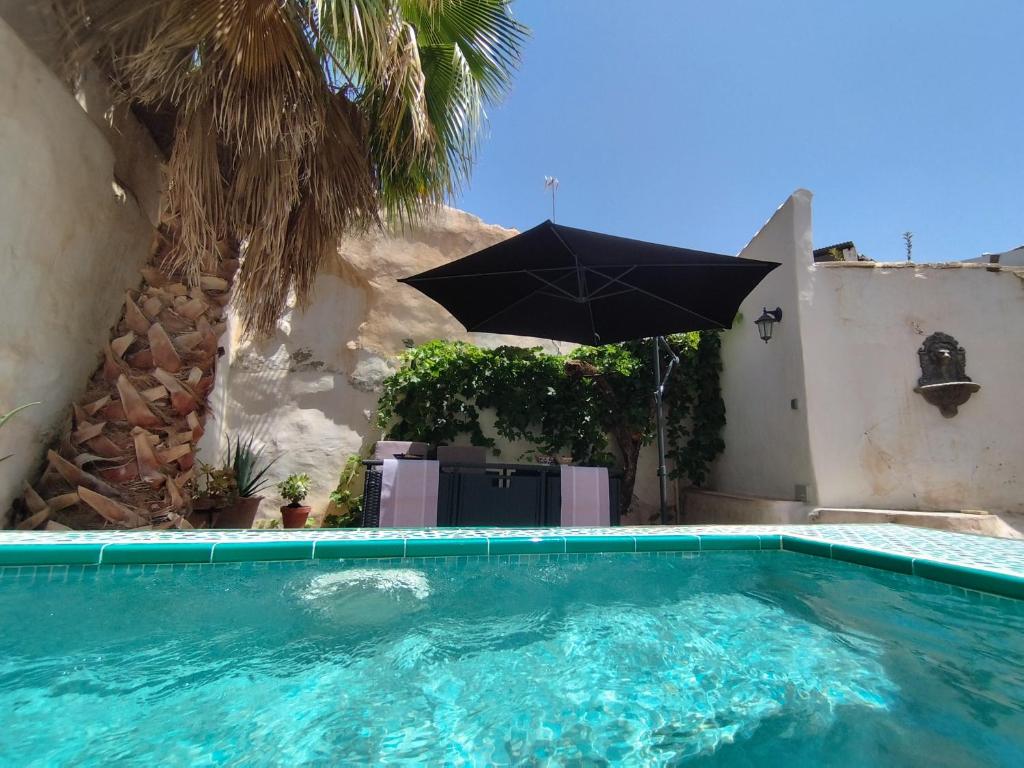 a swimming pool with an umbrella next to a house at Casa Real in Salar