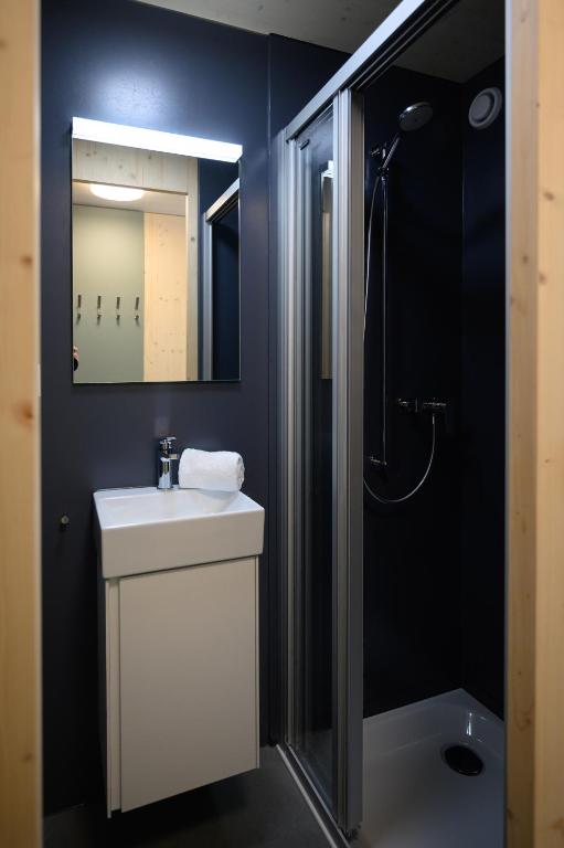 a bathroom with a sink and a shower and a mirror at Sonne Andermatt Swiss Quality Hotel in Andermatt