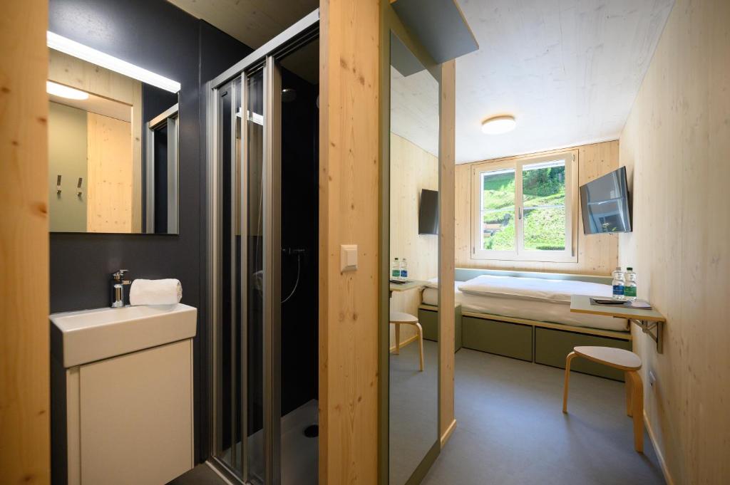 a small bathroom with a sink and a bed at Sonne Andermatt Swiss Quality Hotel in Andermatt