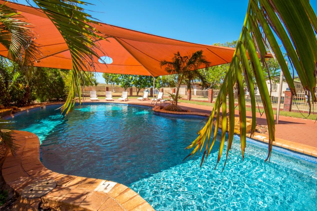 a swimming pool with an orange umbrella and a swimming pool at Discovery Parks - Pilbara, Karratha in Karratha