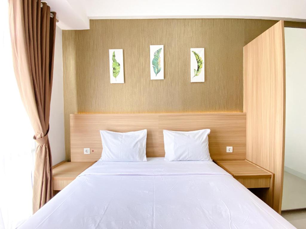 a bedroom with a white bed with two pillows at Best Homey 1BR at 25th Floor Vasanta Innopark Apartment By Travelio in Cikarang