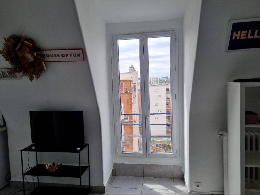 un salon avec une télévision et une fenêtre dans l'établissement Studio cosy, à Aubervilliers