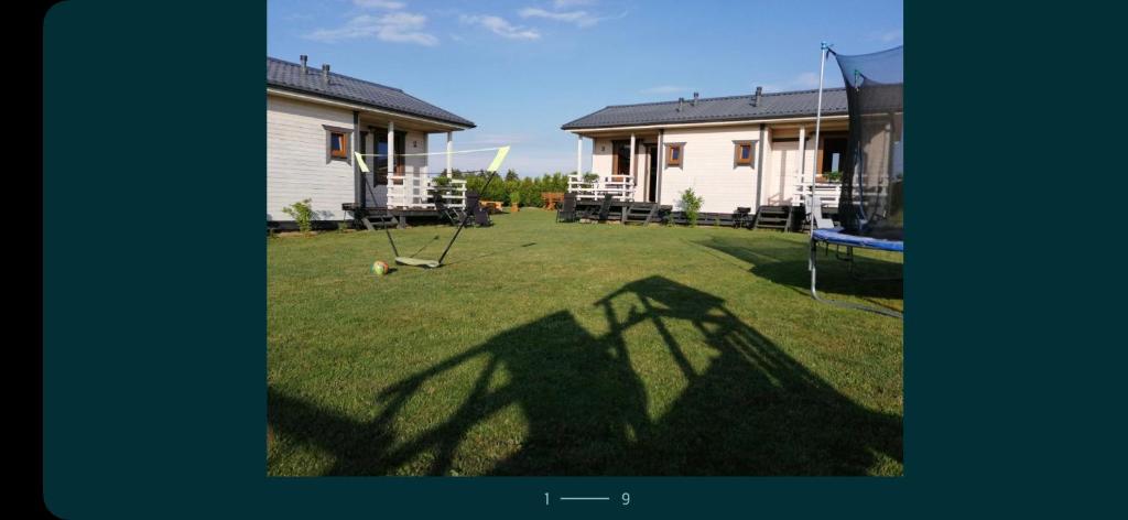 a shadow of a house on a yard with a swing at Domki Cichy Zakątek in Darłowo