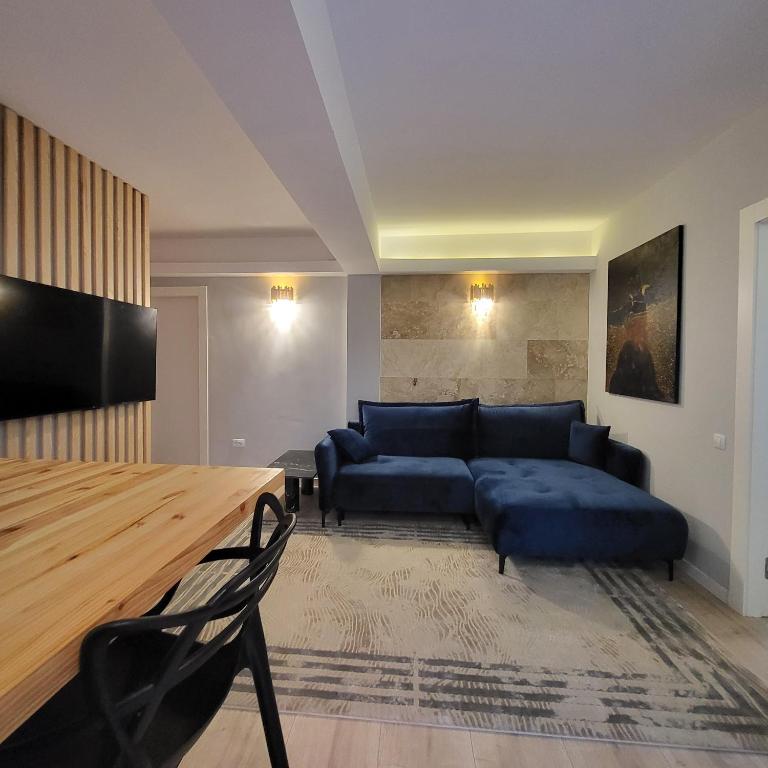 a living room with a blue couch and a table at Apartament cu terasă in Bucharest