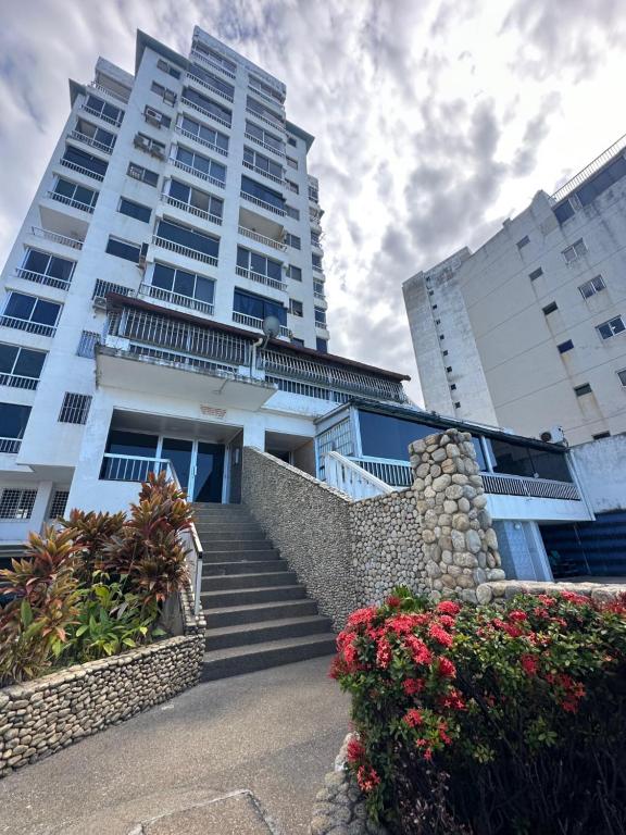 Un edificio con escaleras y flores delante. en Apartamento frente a la playa de la guaira, en San Julián
