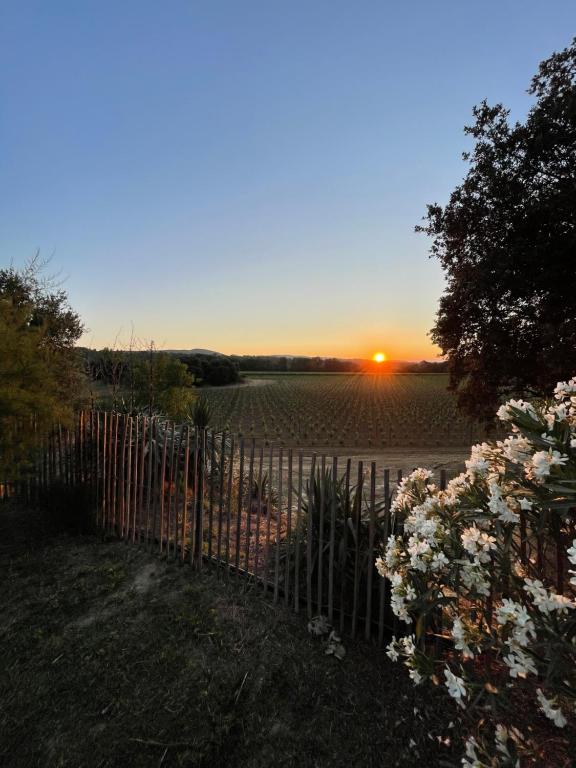 une clôture avec un coucher de soleil en arrière-plan dans l'établissement Domaine Camp Fourca, à Mirabeau