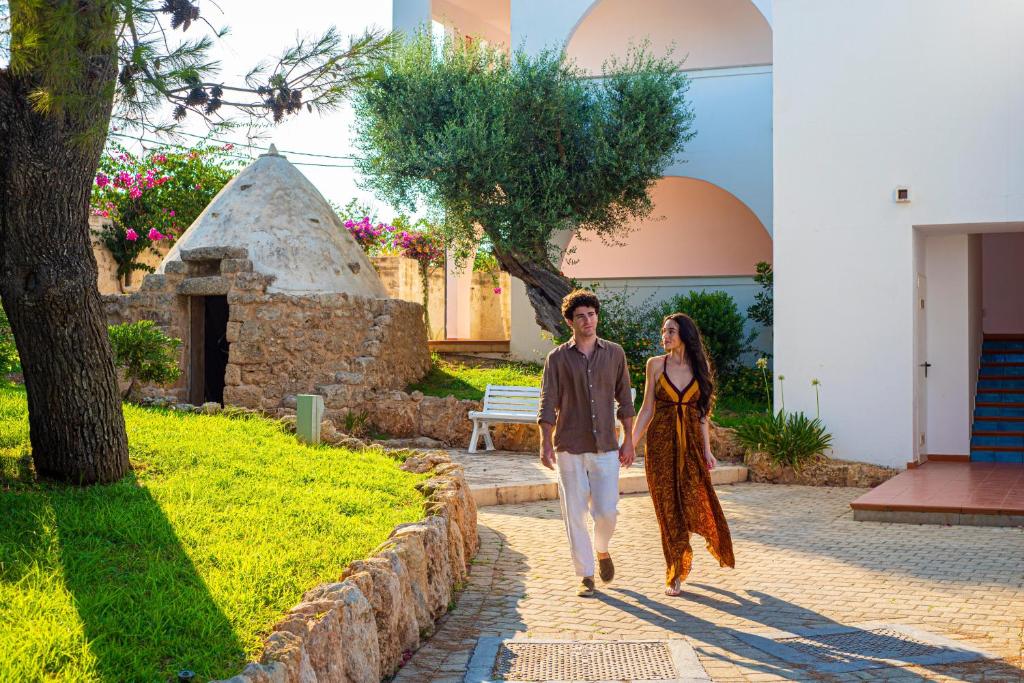 a man and a woman walking down a sidewalk at Pietrablu Resort & Spa - CDSHotels in Polignano a Mare