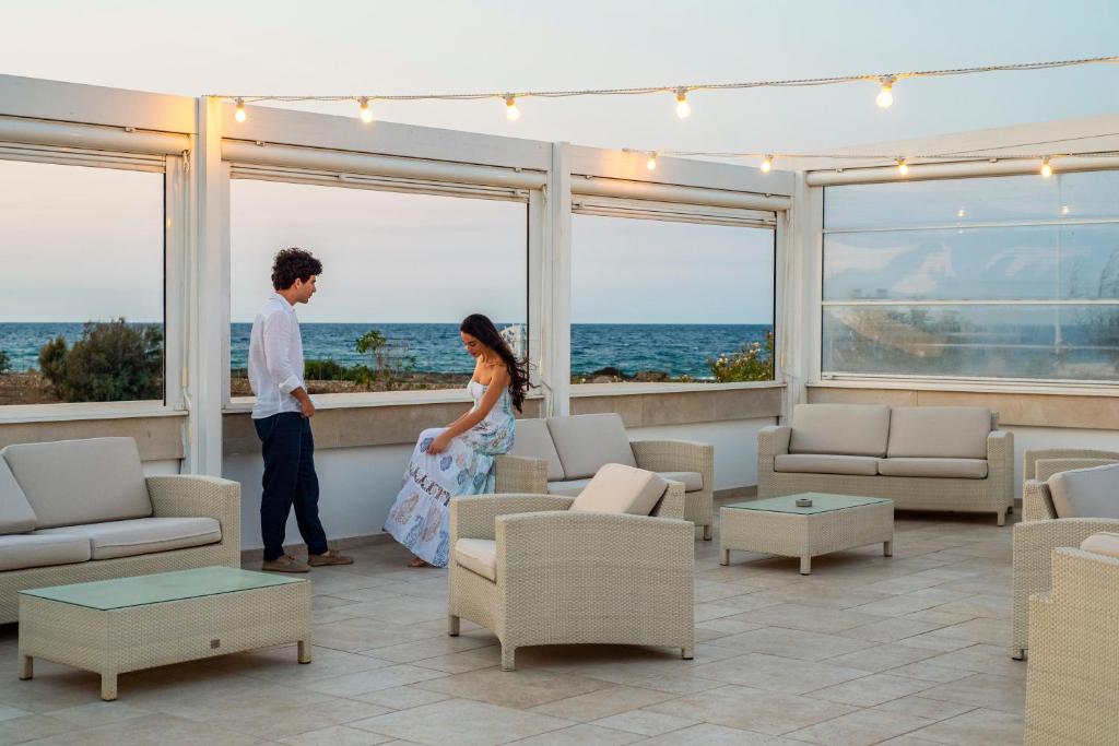 a man and woman standing in a room with the ocean at Pietrablu Resort & Spa - CDSHotels in Polignano a Mare
