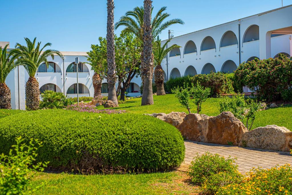a park with palm trees and a building at Pietrablu Resort & Spa - CDSHotels in Polignano a Mare