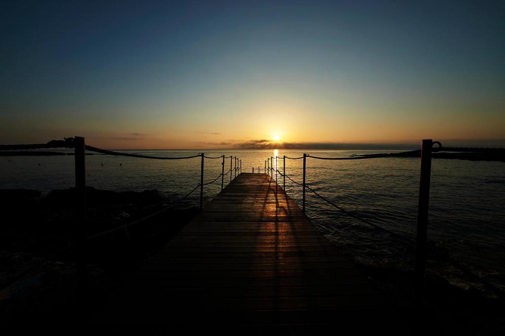 a pier with the sun setting over the water at Pietrablu Resort & Spa - CDSHotels in Polignano a Mare