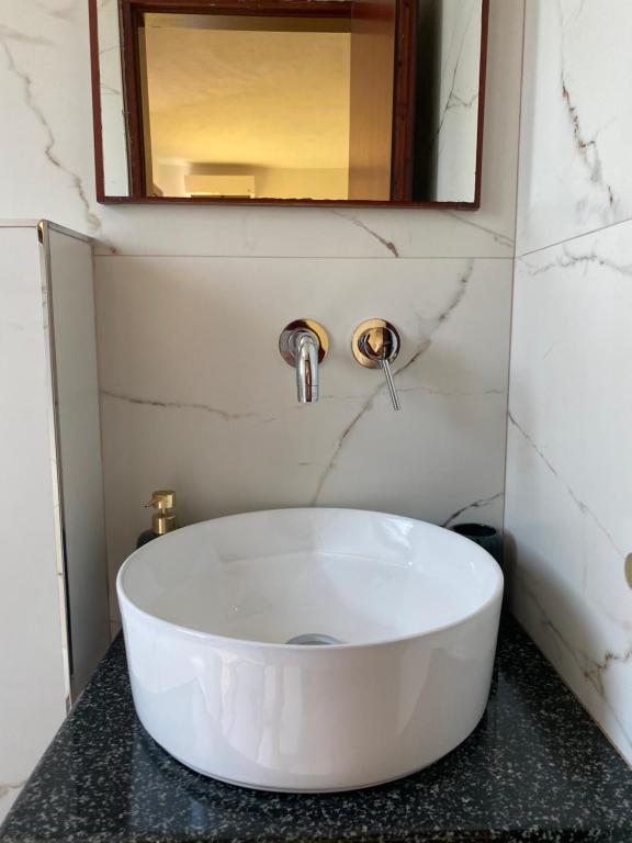 a bathroom with a white sink and a mirror at Hotel Afrodite in Dhërmi