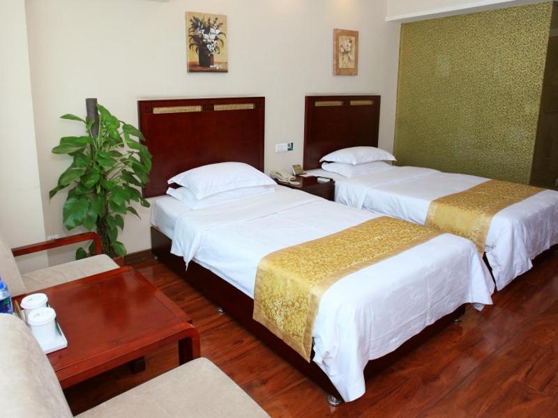 a hotel room with two beds and a plant at GreenTree Eastern AnHui HeFei West Railway Station LinQuan Road Hotel in Hefei