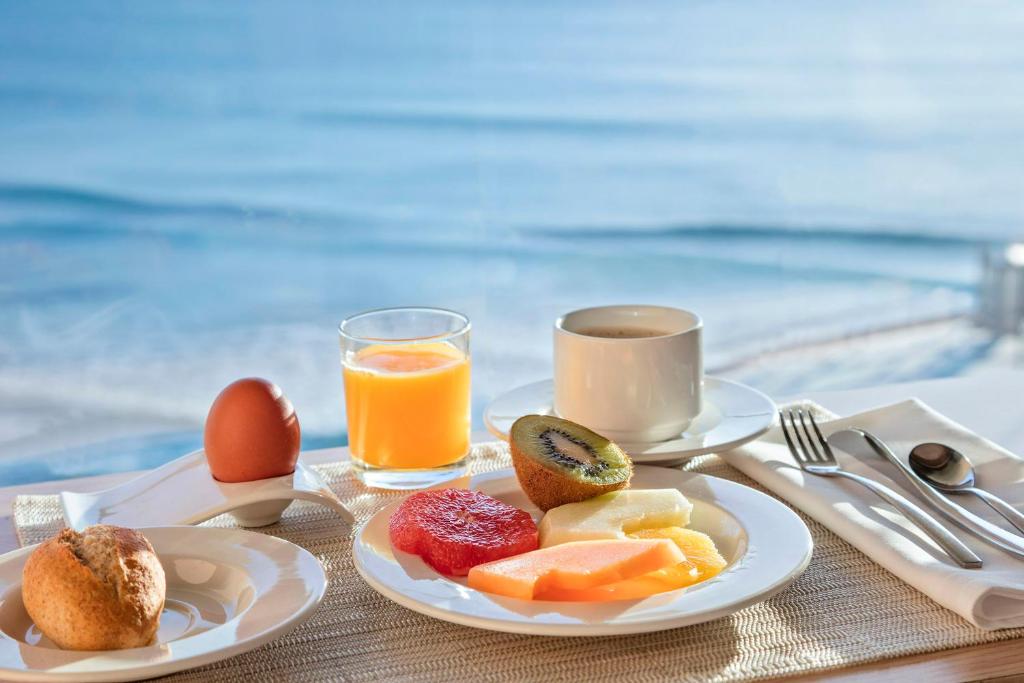 a breakfast plate of fruit and eggs and a cup of coffee at Melia Alicante in Alicante
