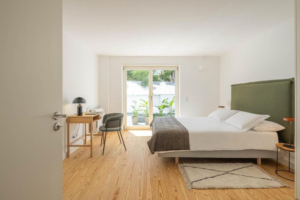 a bedroom with a bed and a desk and a window at Azul Downtown Apartments in Coimbra