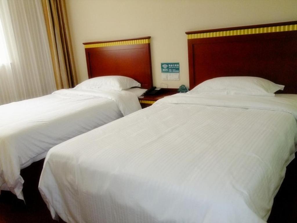 two beds in a hotel room with white sheets at GreenTree Inn Anhui Huangshan Jiangjing District Tiandu Avenue Business Hotel in Huangshan