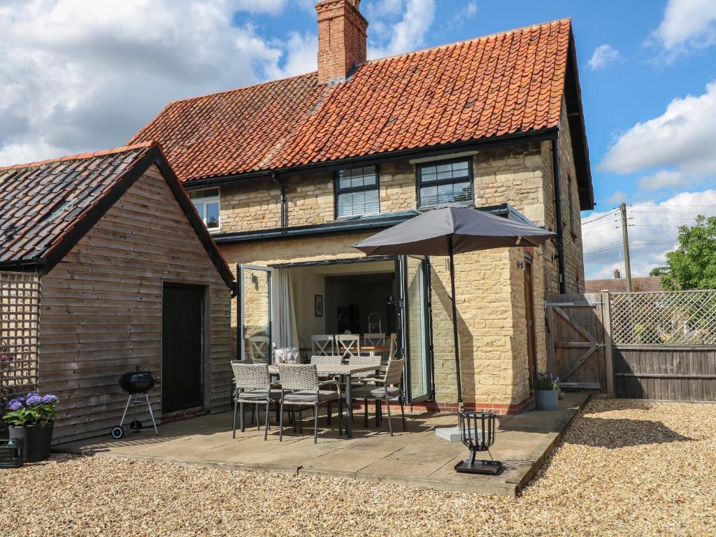 une maison avec une table et un parasol dans l'établissement Lavender Cottage, à Bourne