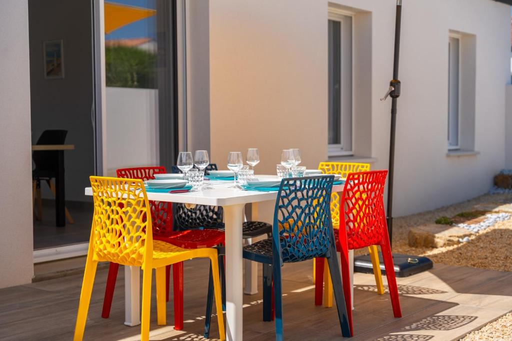une table avec des chaises peintes dans des couleurs différentes dans l'établissement Bienvenue à la Maison 