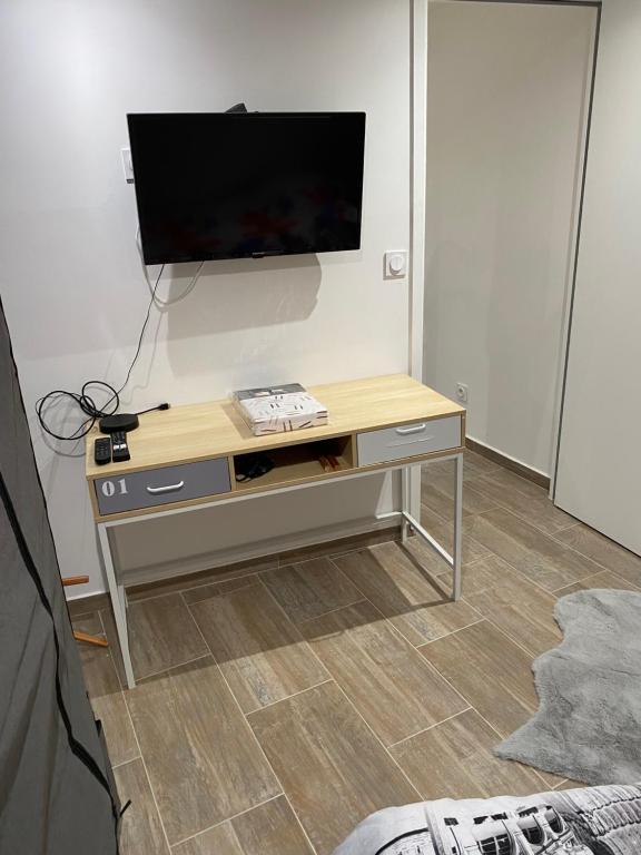 un soggiorno con tavolo e TV appeso a una parete di Pause appart a Lille