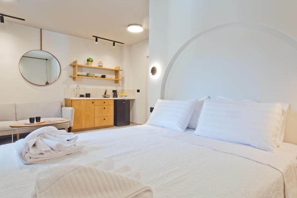 a bedroom with a large white bed with a mirror at Conchilia Houses in Karpathos
