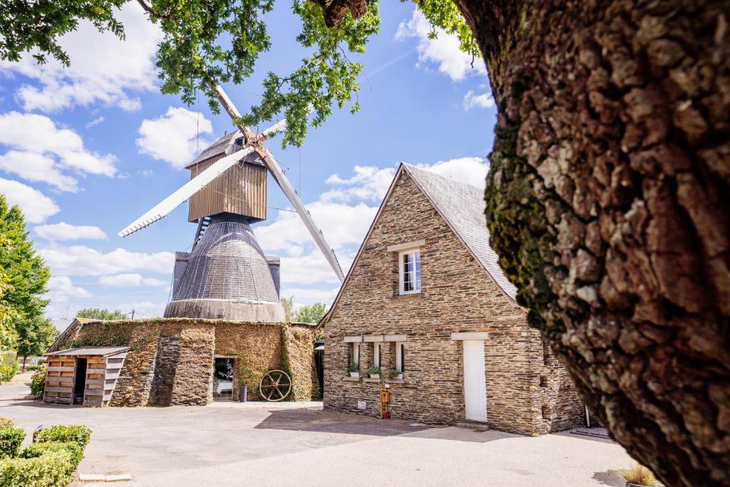 an old mill with a windmill on top of it at Logis Hôtel Domaine du Moulin Cavier - Restaurants & Spa in Avrillé