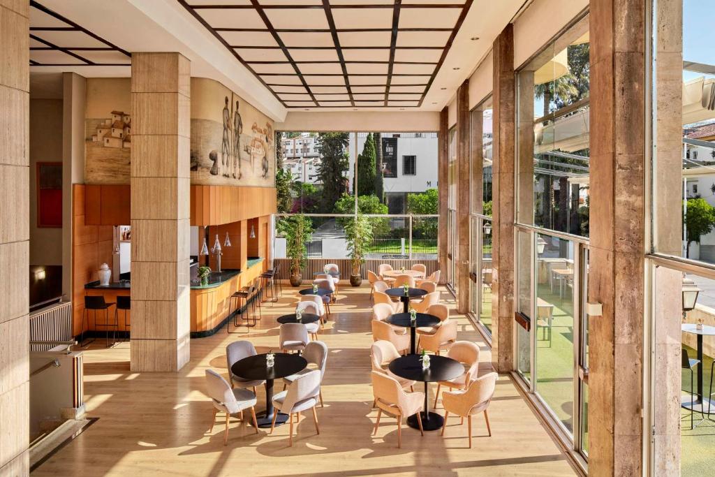 a hallway with tables and chairs in a building at NH Luz Huelva in Huelva