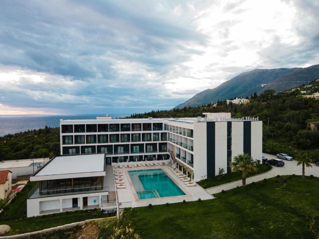 a building with a swimming pool in front of the ocean at Black Diamond Hotel Dhermi in Dhërmi