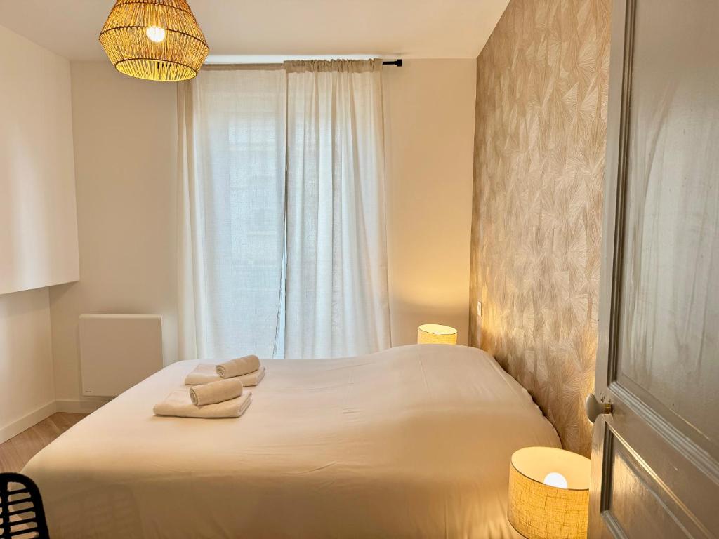 une chambre avec un lit blanc avec des serviettes dessus dans l'établissement Au Mélo' - Proche Gare & Centre, à Reims