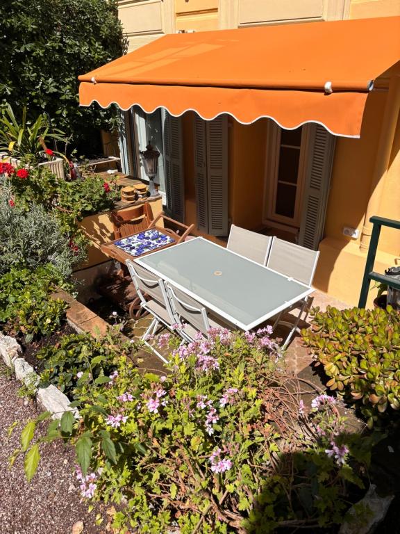 une table et des chaises dans un jardin fleuri dans l'établissement Jardin - 1 chambre - Jean Médecin, à Nice