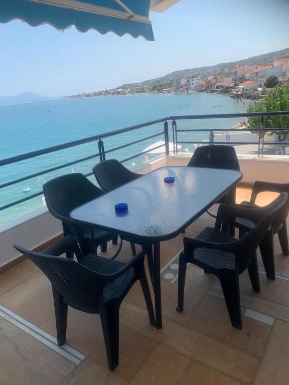 a table and chairs on a balcony with the ocean at Kamari Beachfront Apartments in Xylokastro